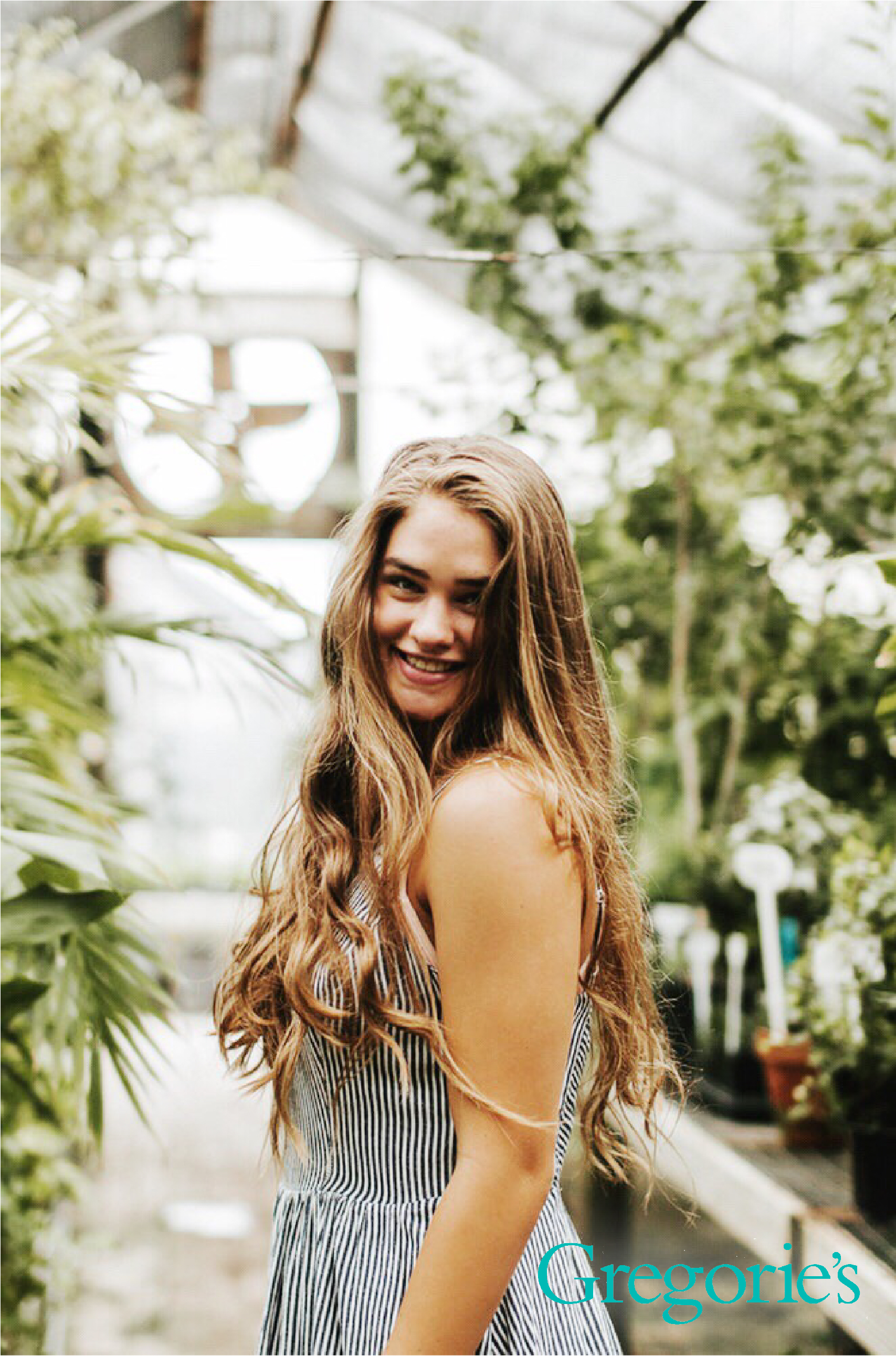 woman with shiny hair standing in a greenhouse