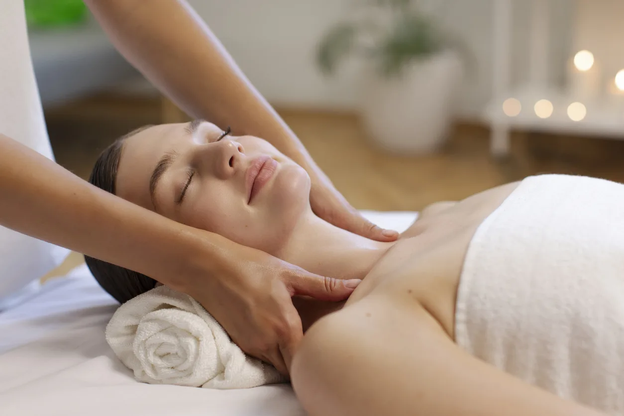 Professional masseuse massaging lady's neck, woman having relaxing therapy and full body massage procedure at spa salon setting Men's hands make a therapeutic neck massage for a girl lying on a massage couch in a massage spa with dark lighting. Close-up. Dark Key